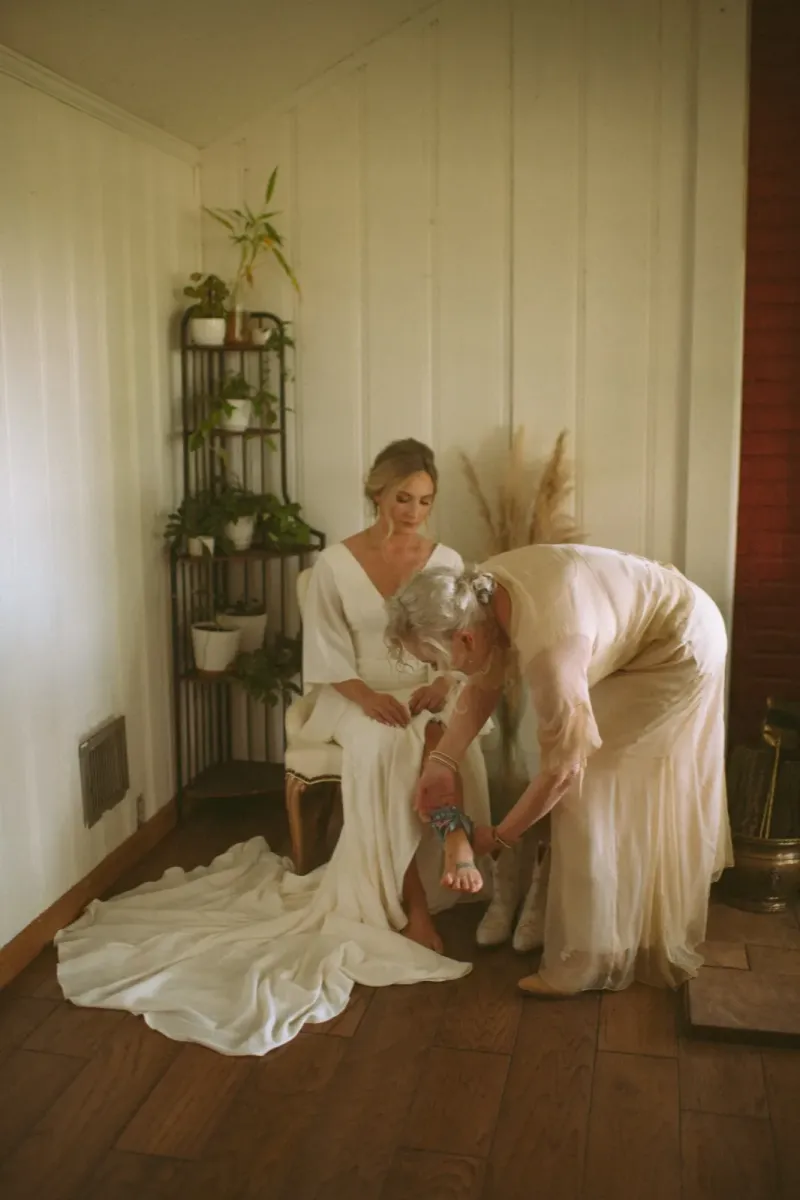 Bride putting on blue garter with elegant flowing wedding dress
