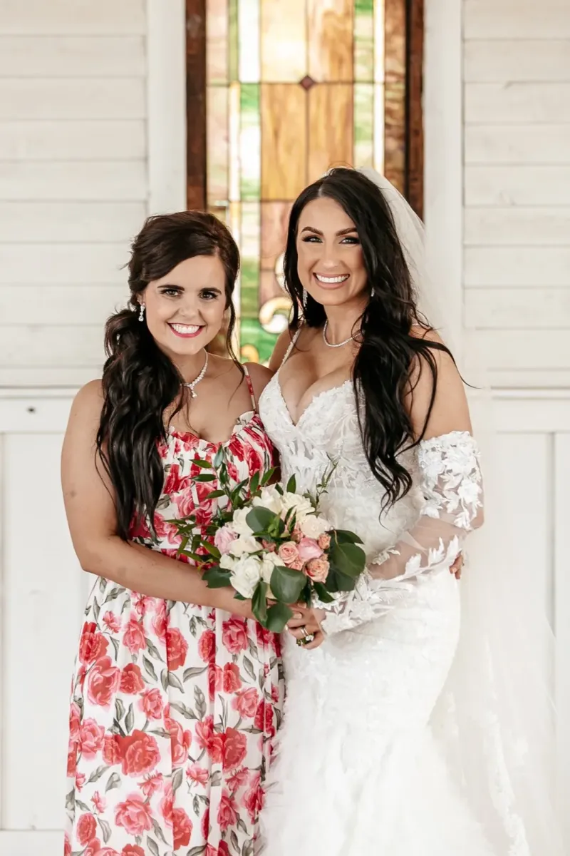 Bride and bridesmaid with long dark hair and lace wedding dress