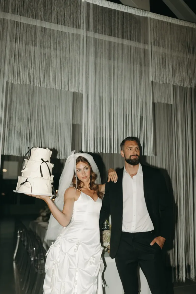 Modern minimalist wedding reception with white cake and string curtain backdrop