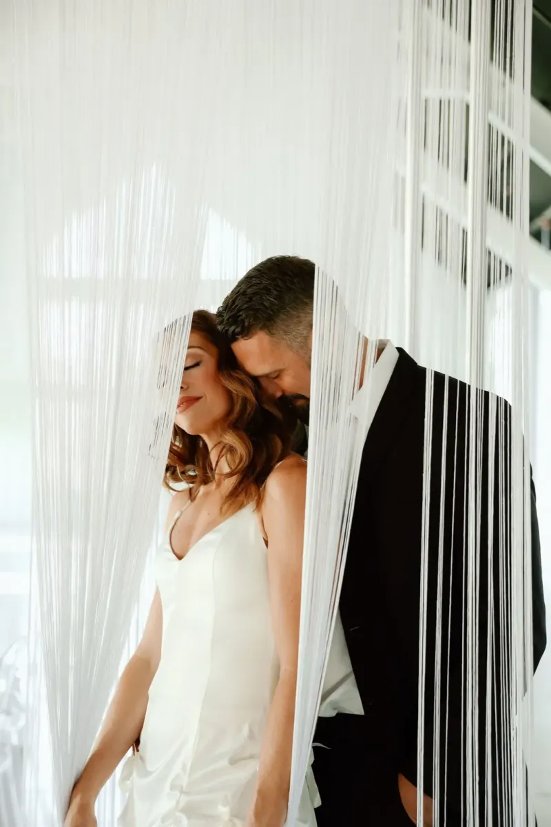 Romantic wedding couple portrait behind white string curtain