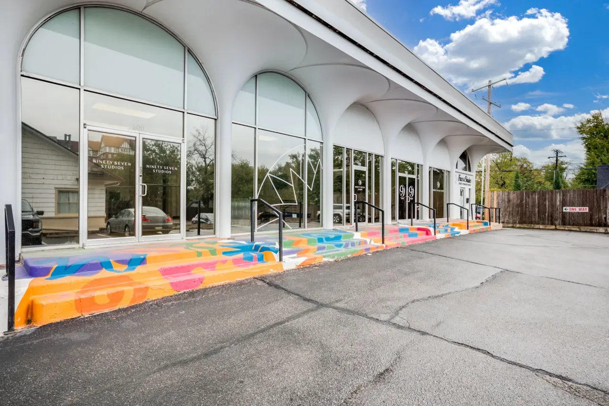 Modern hair salon exterior with colorful geometric mural and arched windows