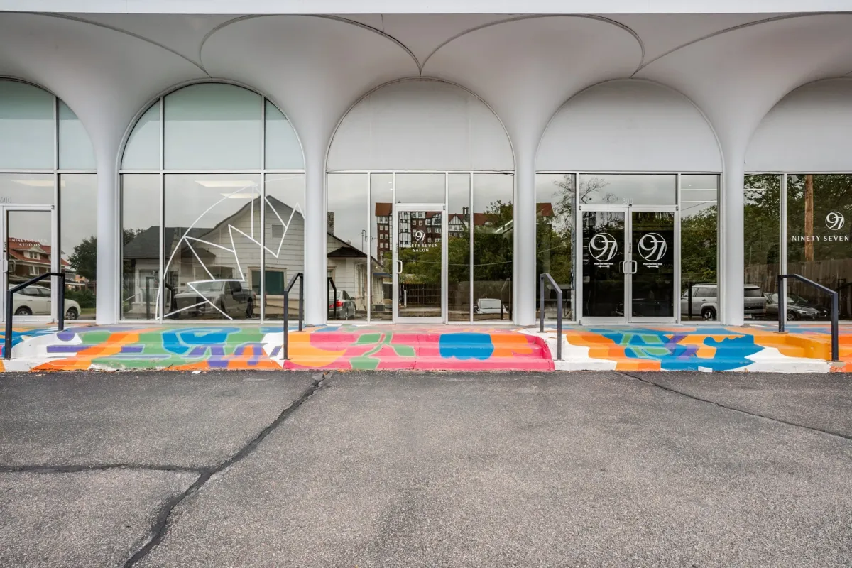Contemporary salon storefront with arched architectural details and artistic sidewalk design