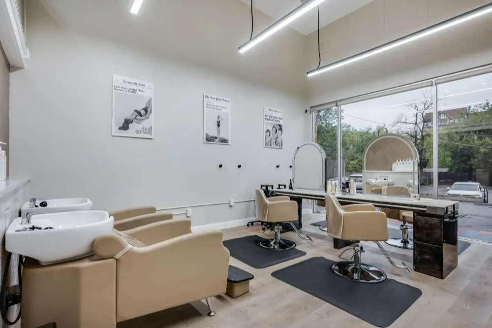 Professional salon shampoo area with beige backwash chairs and modern fixtures